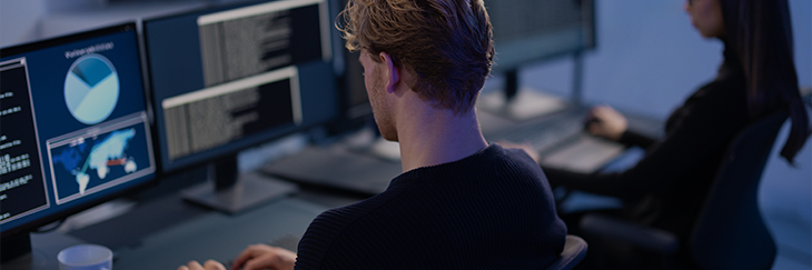 Image of cyber threat intelligence analyst working at a desk with multiple computer systems 