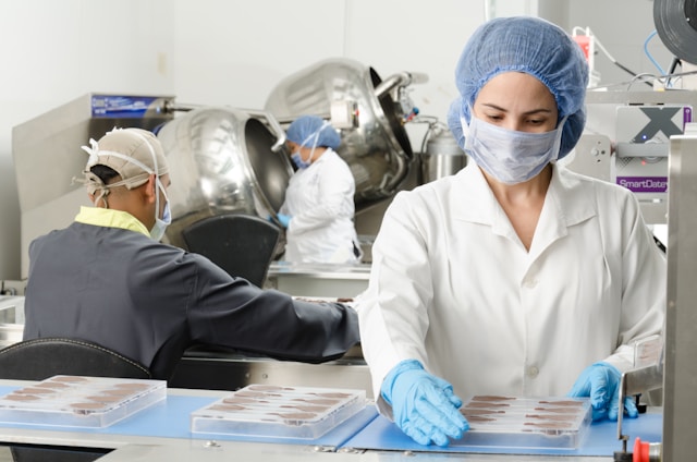 Three people in lab coats and hairnets work in a laboratory designed for staff efficiency.