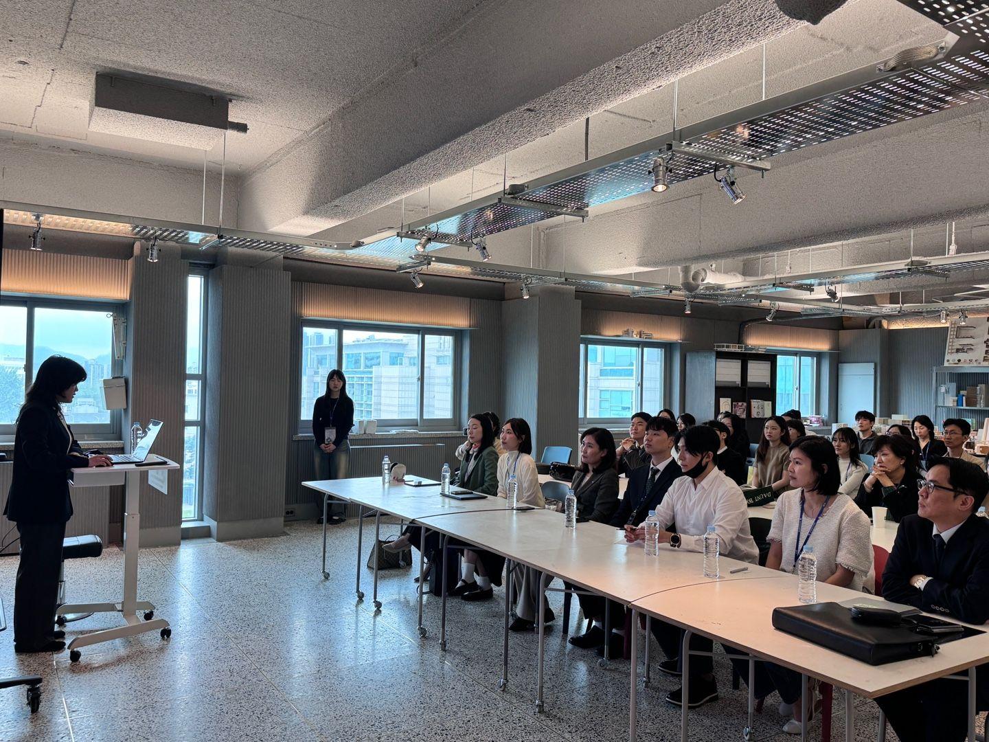 A person standing in front of a podium in a room with people sitting at tables

AI-generated content may be incorrect.