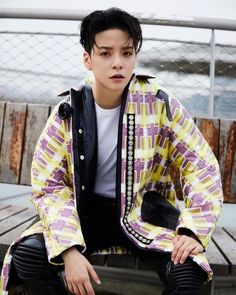 This  contain an image of Amber Liu  sitting on top of a wooden bench wearing a yellow and purple jacket