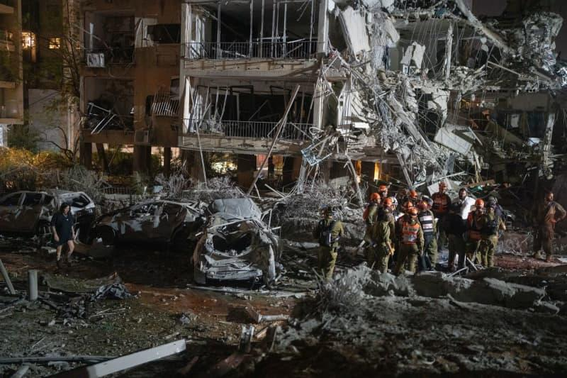 Israeli firefighters inspect the aftermath of a missile strike in Ramat Gan, near Tel Aviv, where several cars were destroyed. The strike was part of a large-scale Iranian missile barrage on June 13, launched in response to Israeli strikes on senior military figures and strategic sites in Iran. Ilia Yefimovich/dpa