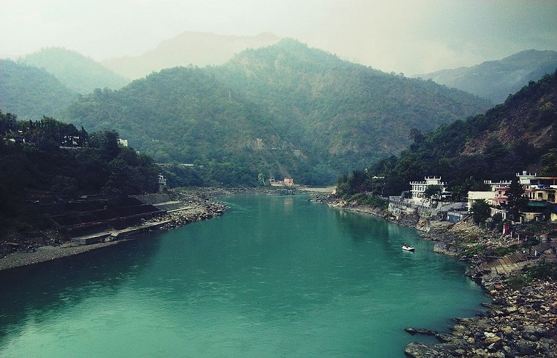 Serene view of Rishikesh, Uttarakhand, showcasing the Ganga River, iconic Lakshman Jhula, and yoga retreats amid the Himalayas.