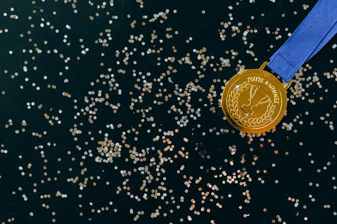 Close-Up Shot of a Gold Medal on a Black Surface
