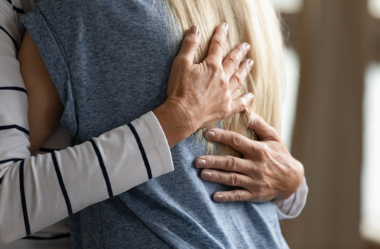 A senior parent tightly hugs their adult child during the moving process.