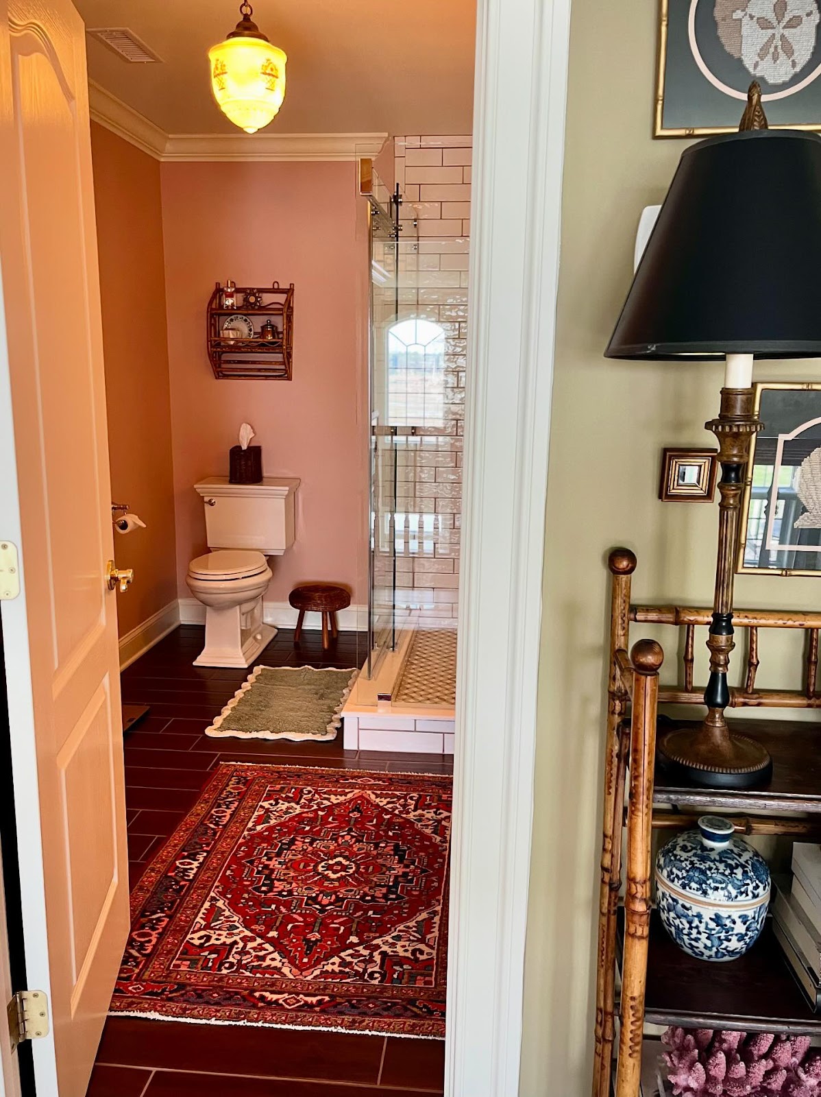 A cozy bathroom with warm peach walls, a Persian rug, and a glass-enclosed shower