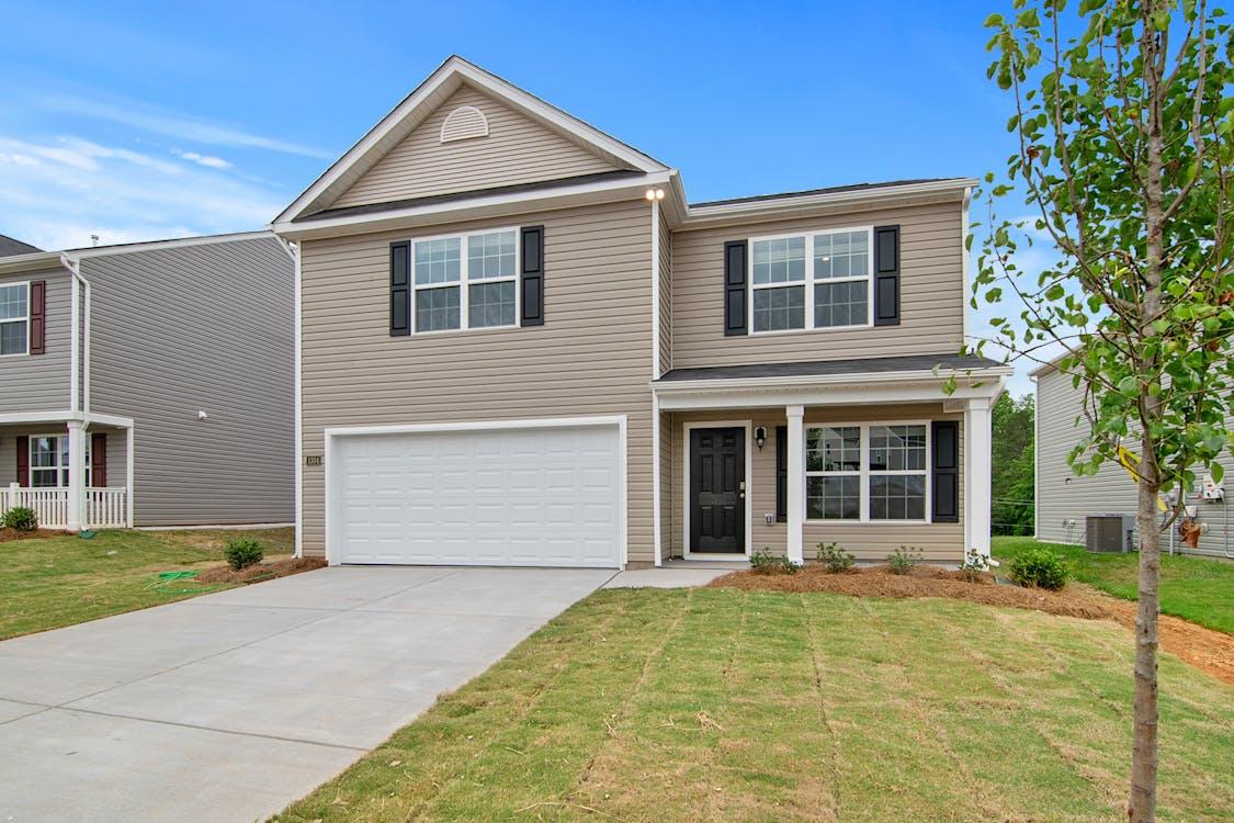 Free Modern two-story house in a suburban neighborhood with a well-maintained lawn. Stock Photo