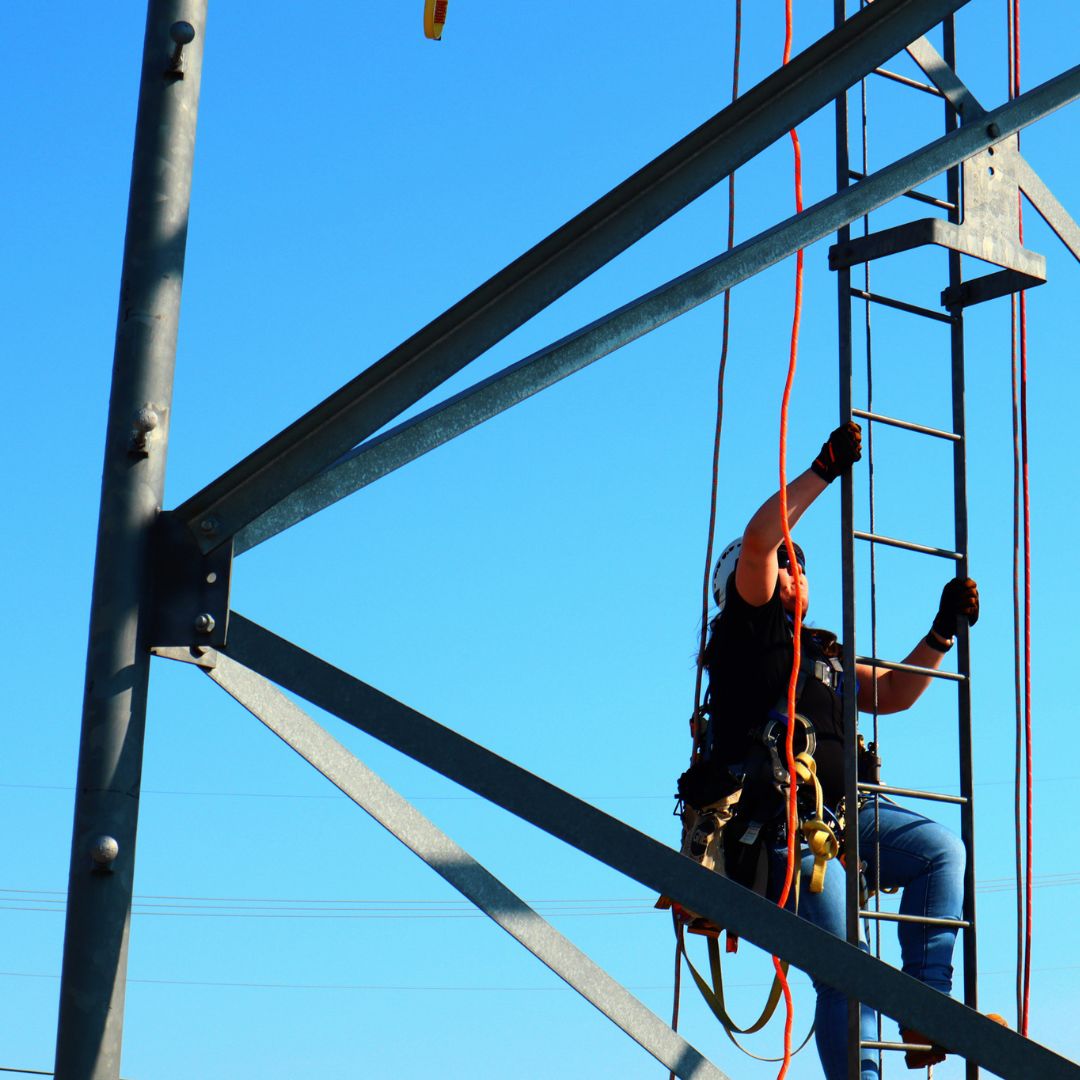 Female Tower Technician student climbing a steel telecommunications tower during hands-on training at Pinnacle Career Institute. PCI’s hybrid trade school program offers real-world tower climbing and rigging experience to prepare students for careers in telecom and wireless infrastructure.