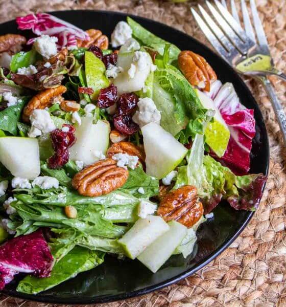 Winter salad with cranberries, pecans and cabbage on black plate