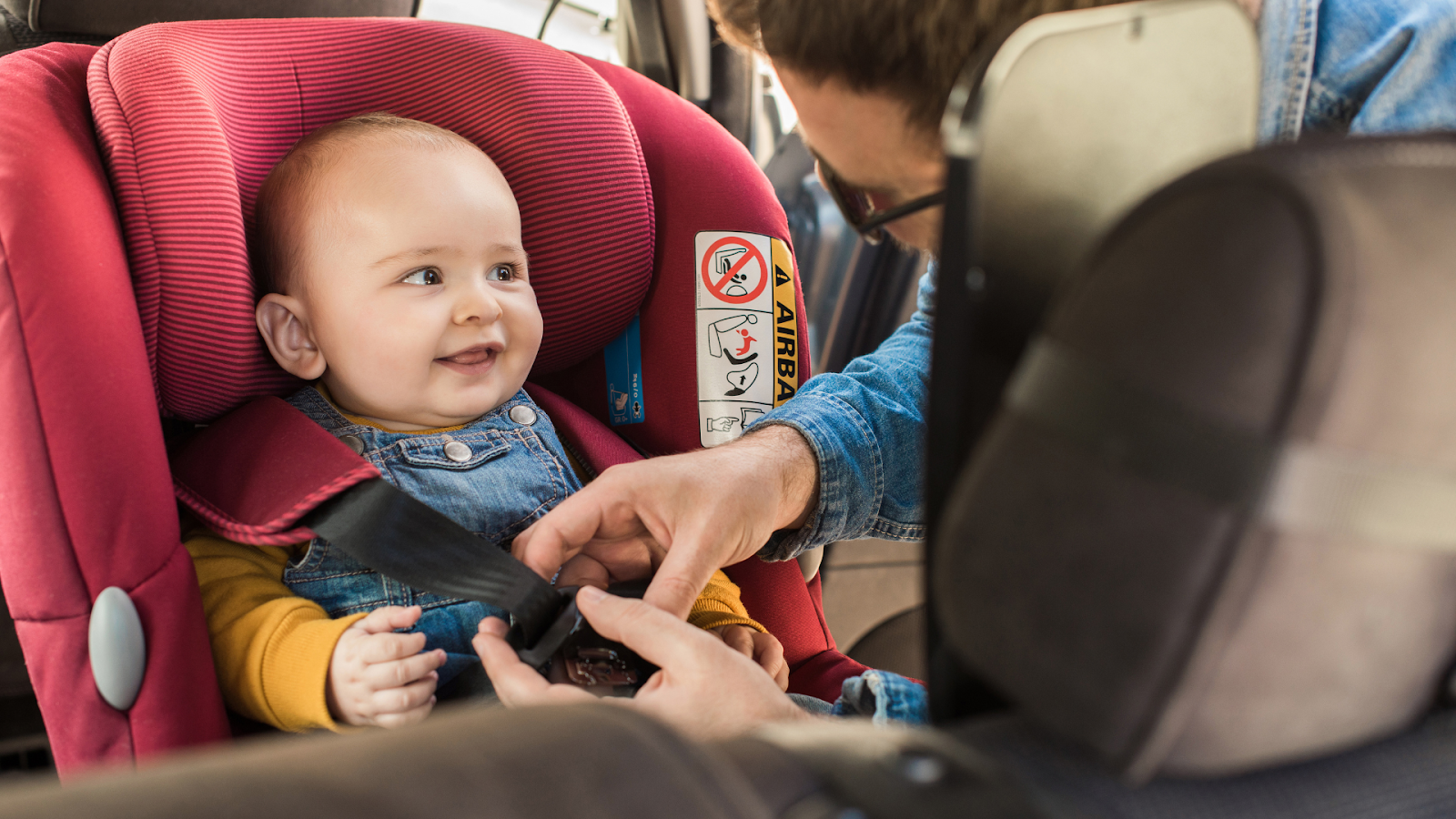 Baby smiling while mom is buckling baby into a car seat // Healthier Baby Today