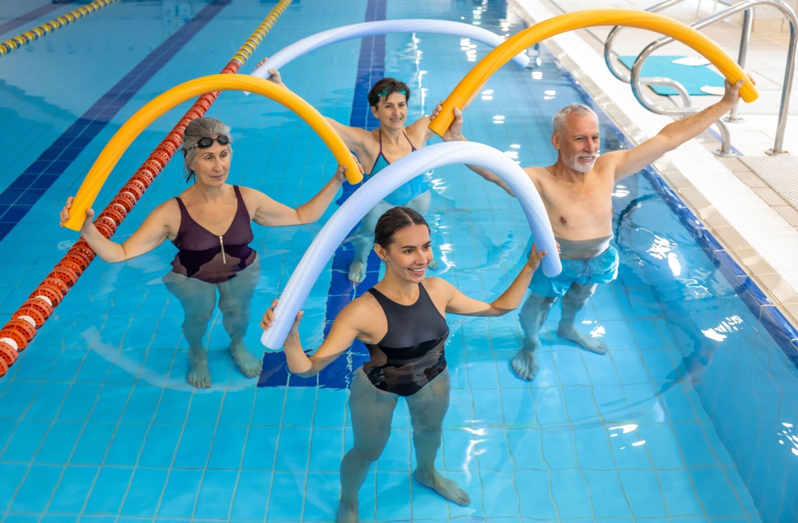 A professional instructor leads a group of older adults in various water exercises.