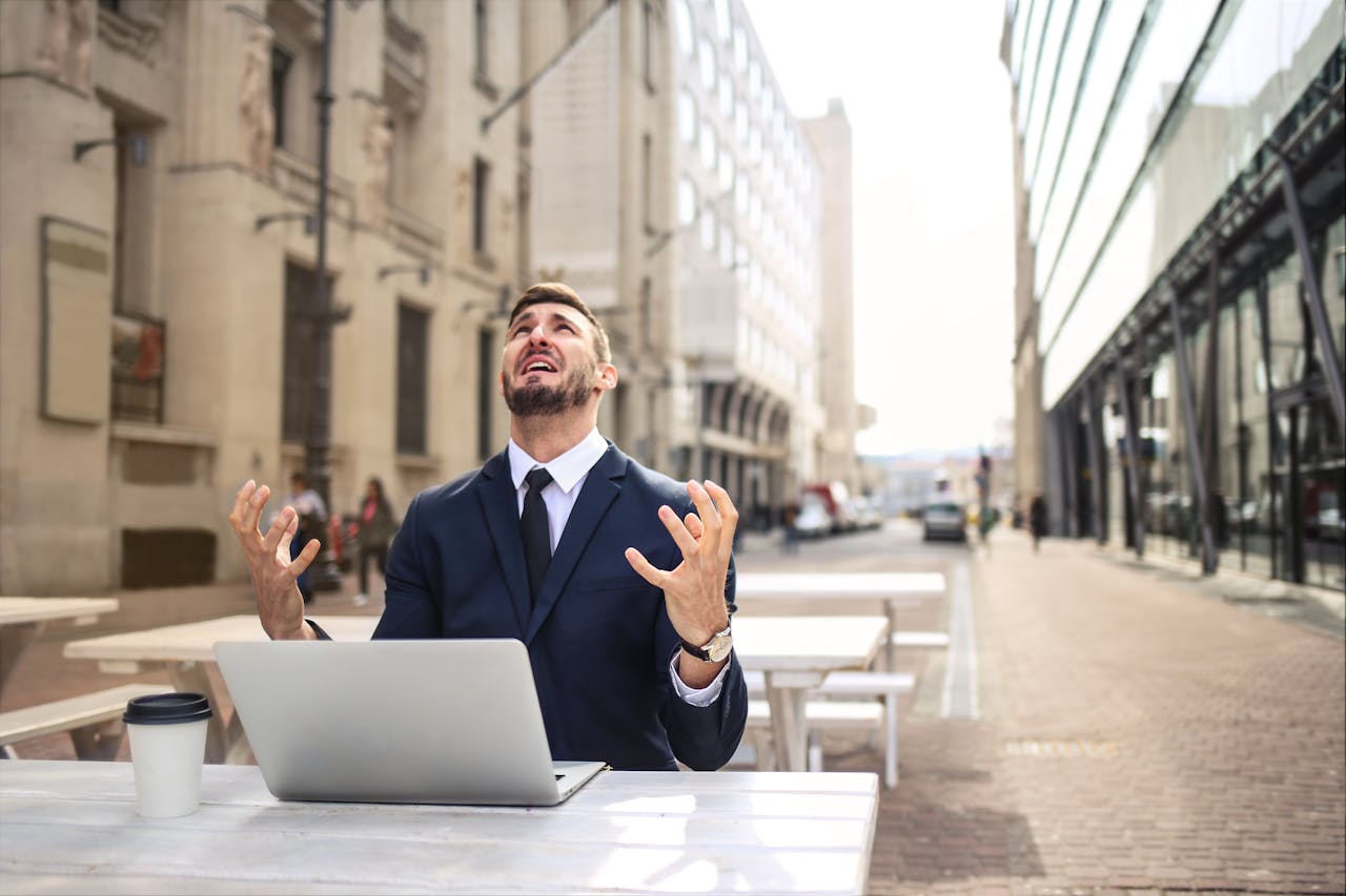 A man in a business suit sits at a table, showing disappointment on his face