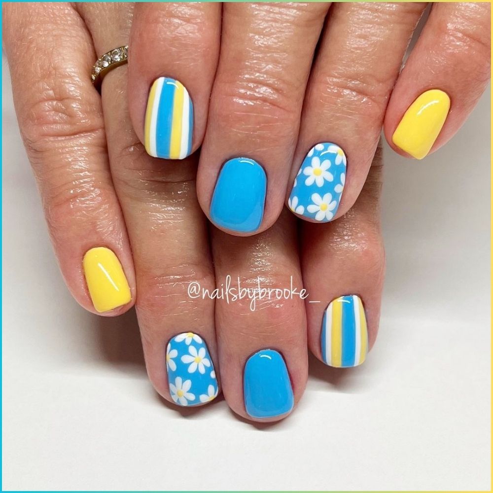 Close up of hands with flowered designed blue nails having  bright yellow and blue shades