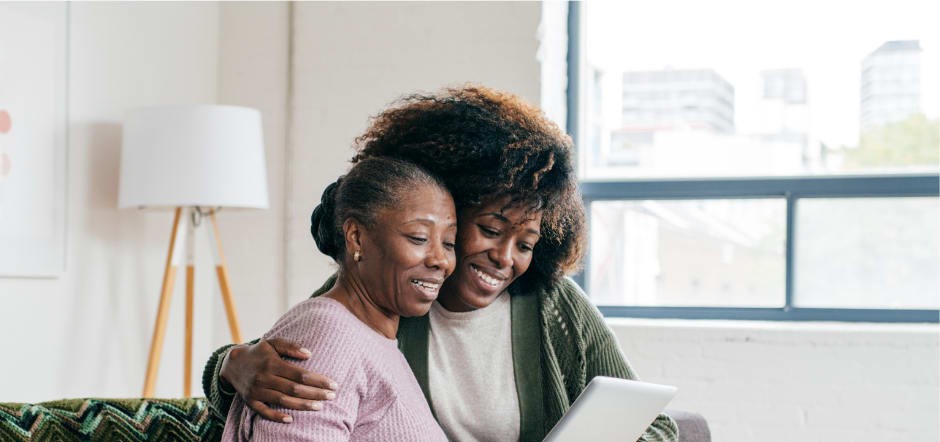 A woman and what appears to be her mother smiling at a mobile tablet device