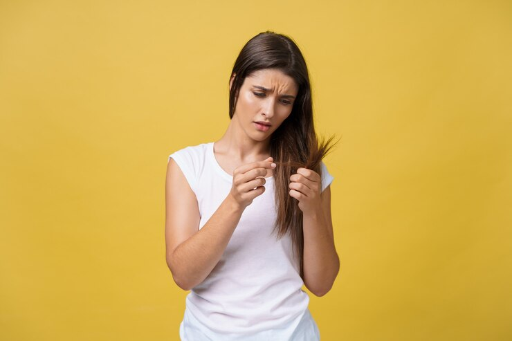 Woman hand holding her long hair with looking at damaged splitting ends