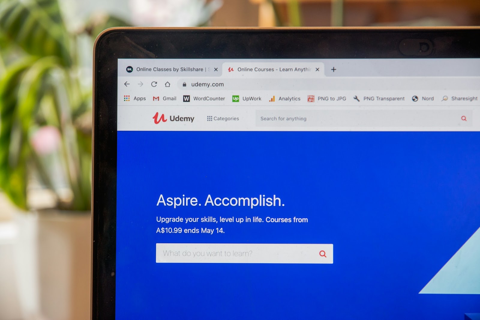 Close-up view of a laptop screen displaying the homepage of Udemy, an online course platform with the headline 'Aspire. Accomplish.' and a search bar for learning new skills, encapsulating the essence of how to create online courses.