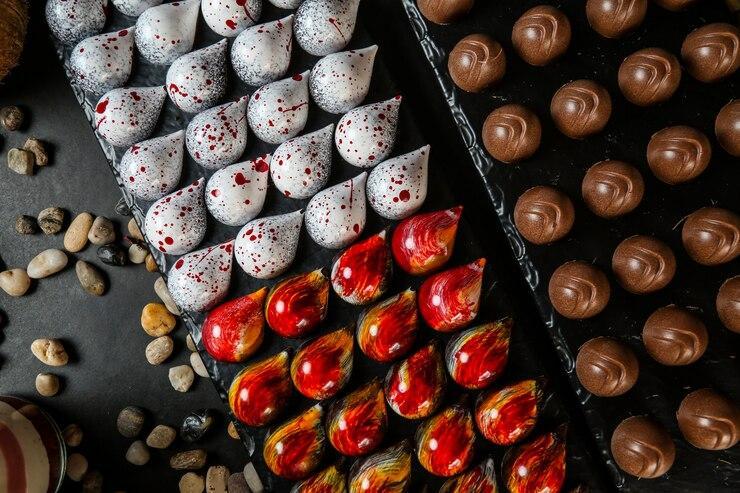 Top view colored decorative chocolates on a stand with stones on a black background