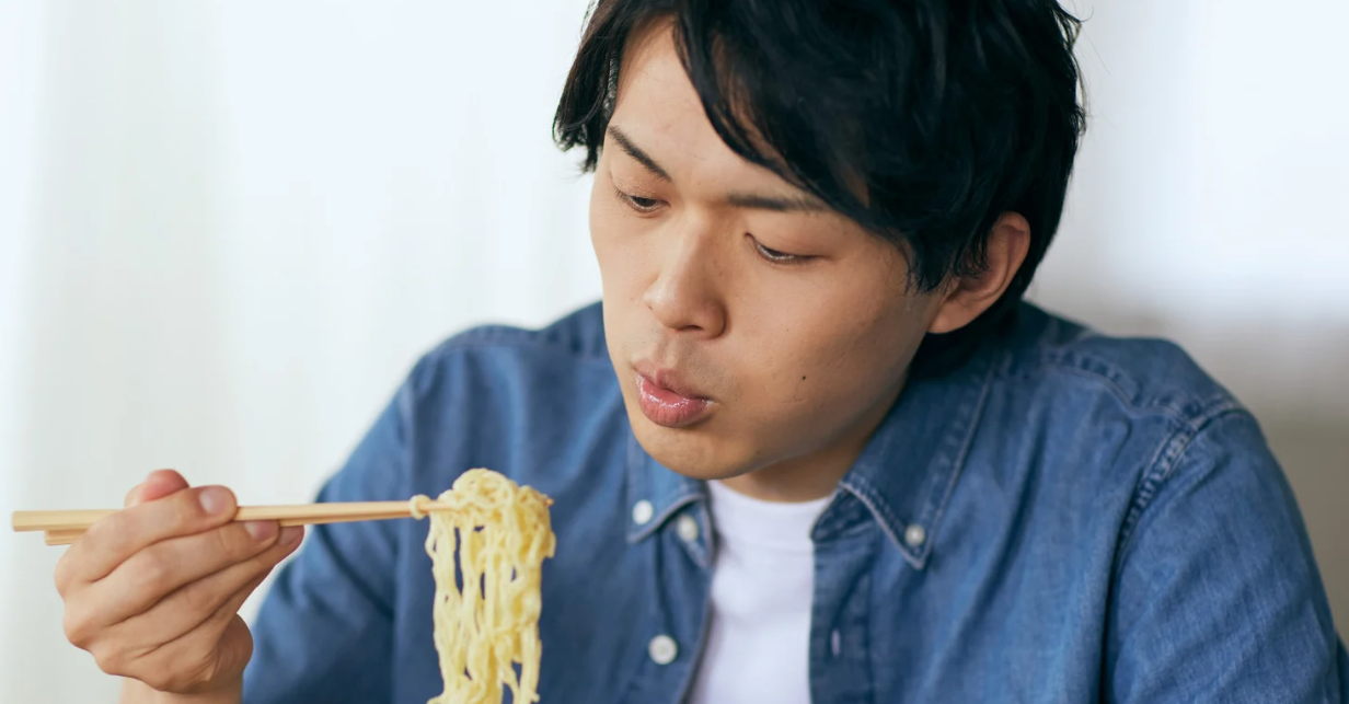 (Mann isst Ramen mit Stäbchen)