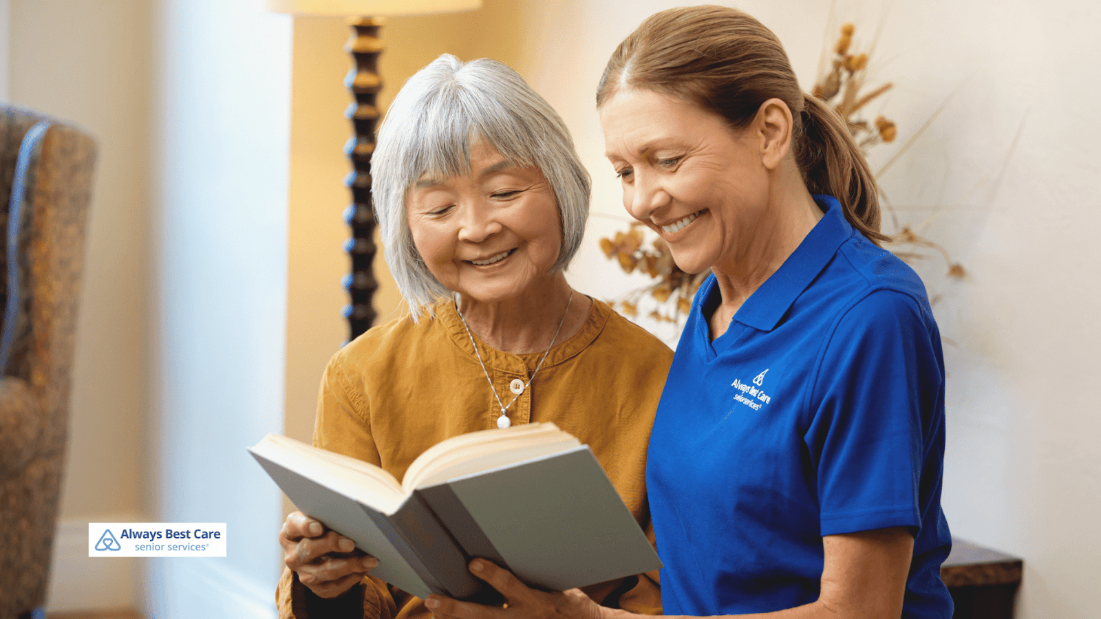 This is an image of a senior and a caregiver reading together