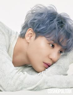 This contain  an image   Kim Junsu blue hair laying on top of a white bed next to a pillow