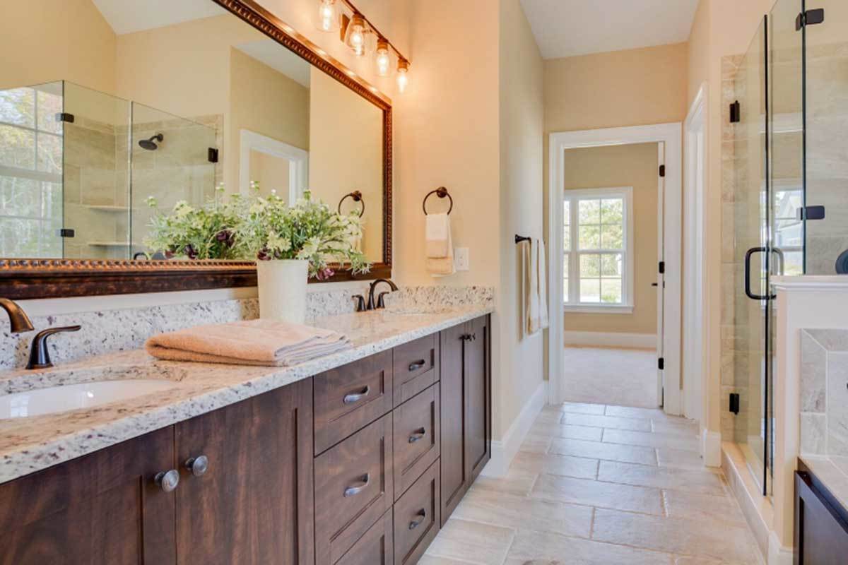 The primary bathroom offers a toilet room, walk-in shower, and a dual sink vanity paired with a rectangular mirror.