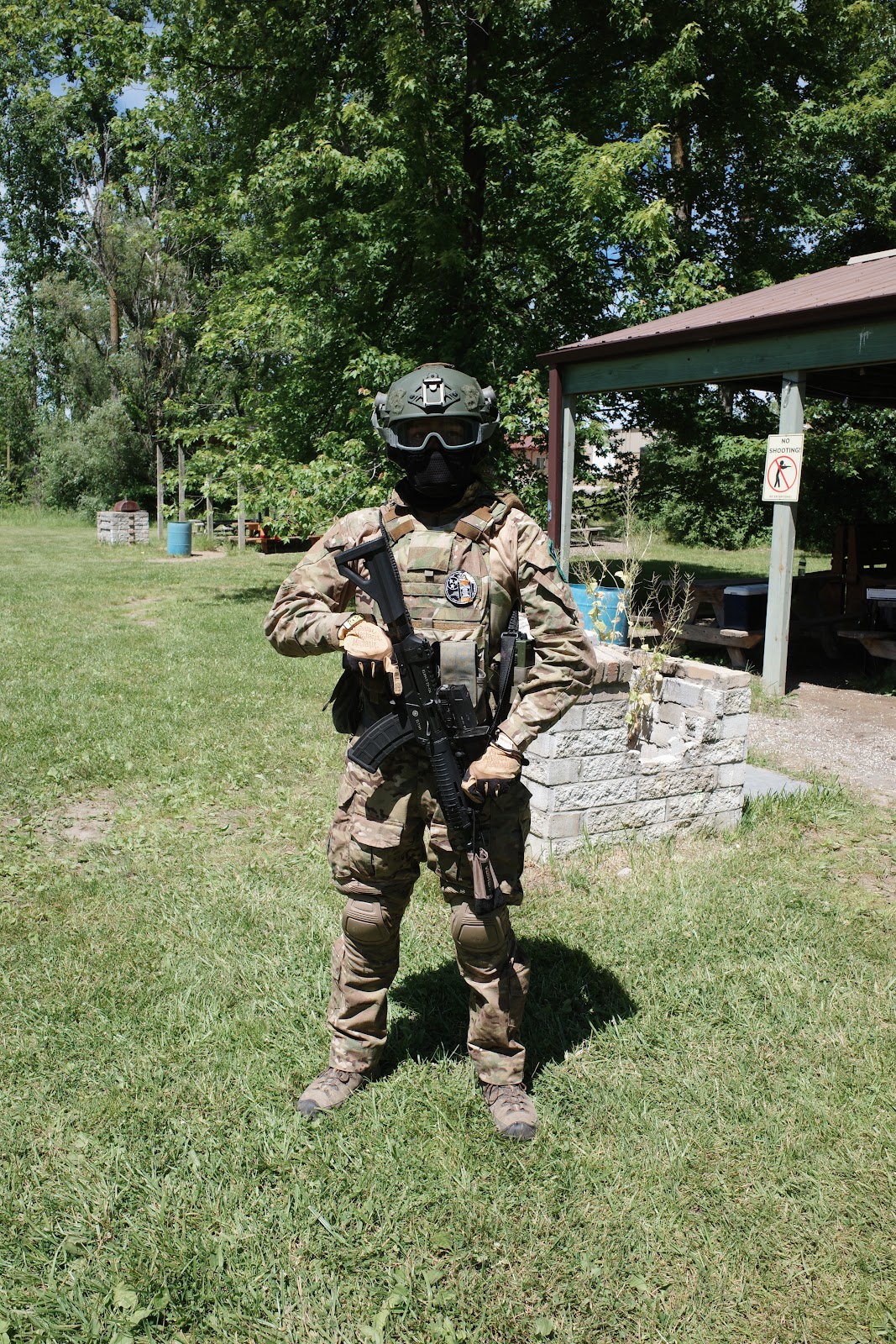 Man in full airsoft militaria kit, camouflage outfit, with airsoft rifle and airsoft face mask.