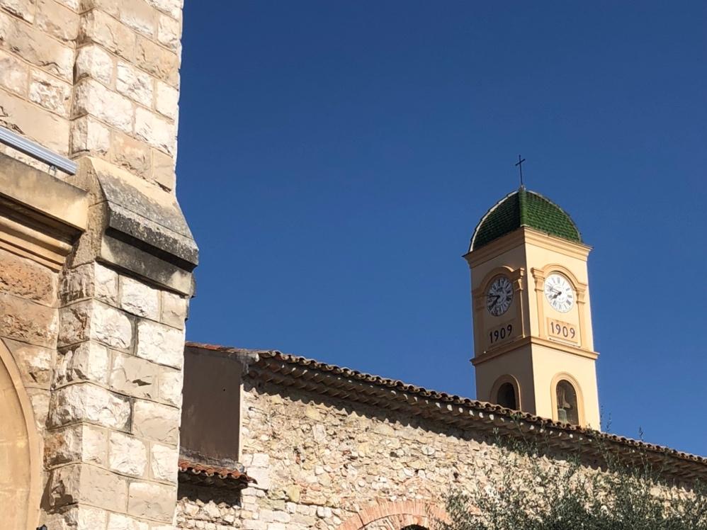 A clock tower with a cross on top of a building

Description automatically generated