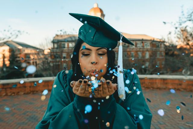 woman graduating in cap and gown blowing confetti