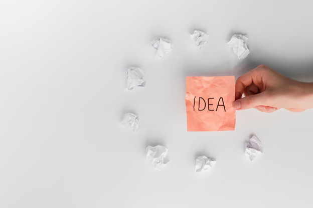 A hand holding a piece of paper next to crumpled paper

Description automatically generated