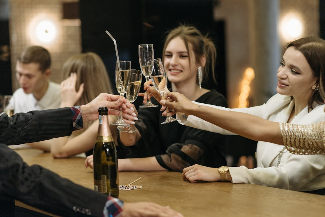 Free Friends clinking glasses in a lively bar setting, celebrating together. Stock Photo