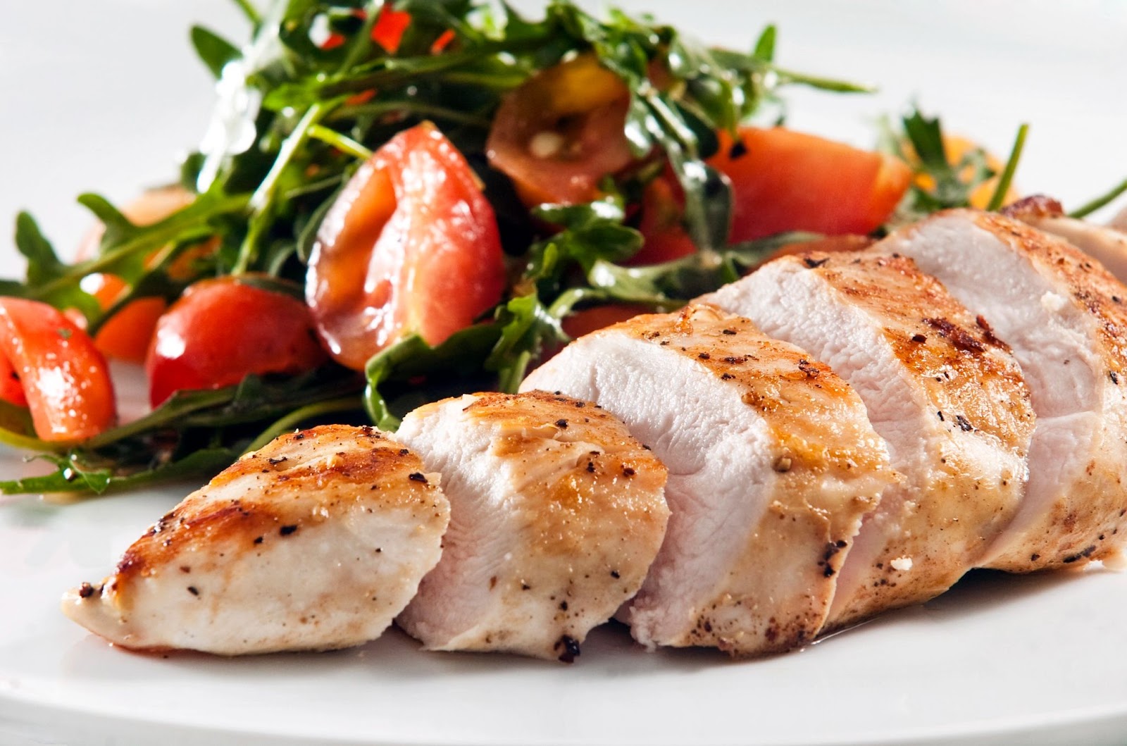 Grilled and seasoned chicken breast served with an arugula and tomato salad on the side