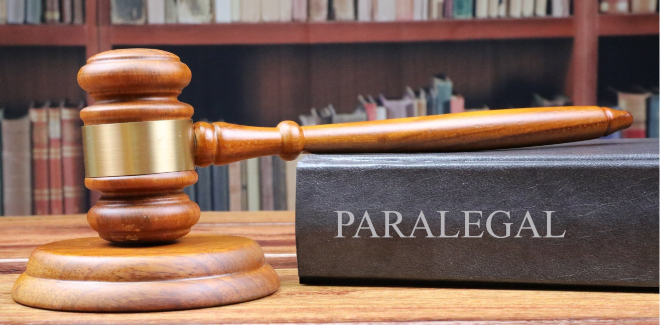 Legal office of lawyers, hammer on a desk with book with paralegal written in a courtroom with blurred  bookshelf in the background.