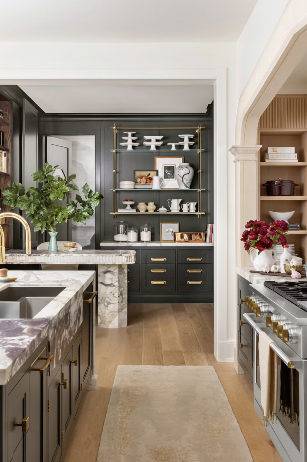 Beautiful modern style kitchen with marble countertops, black accent cabinetry and gold handles. 