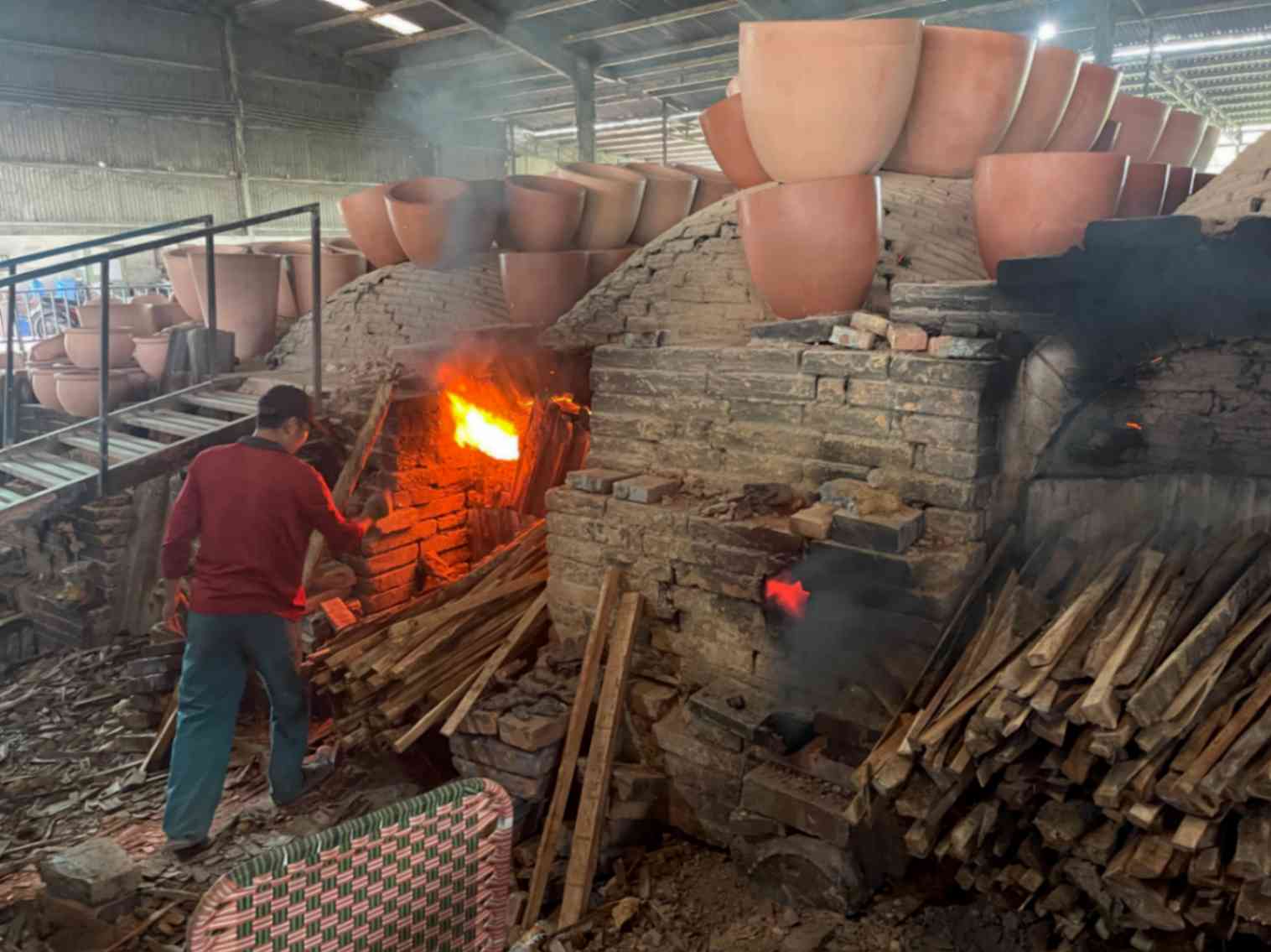 Image of a worker tending a wood-fired kiln
