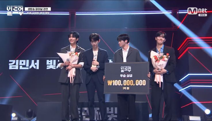 This contain an image of Build Up: Vocal Boy Group Survival standing on stage with flowers in their hands and one man holding a sign