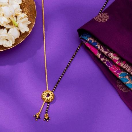 A gold necklace with a round pendant and a bowl of flowers

AI-generated content may be incorrect.