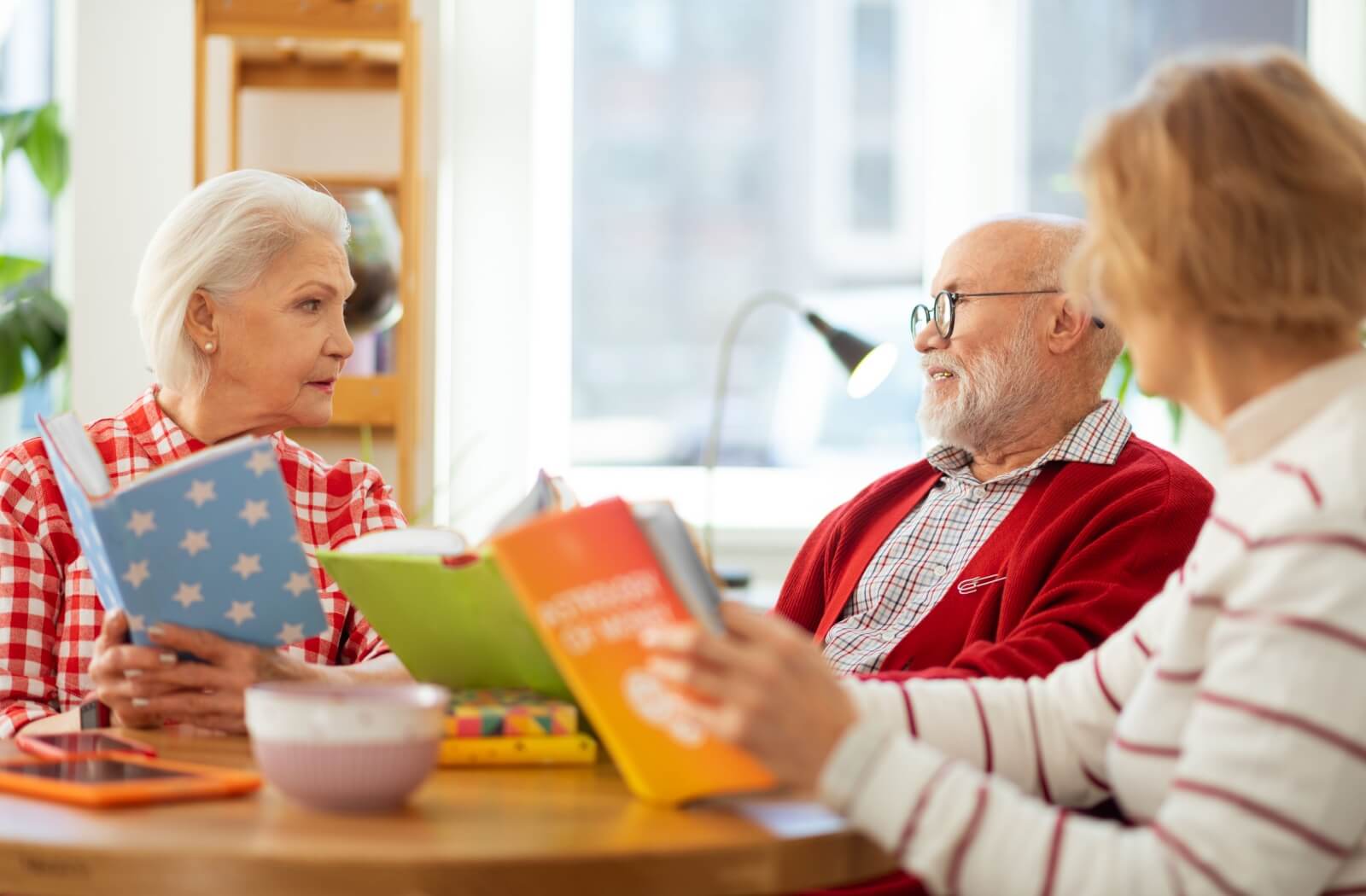 A group of seniors sit around the table discussing the latest book they're reading in their book club