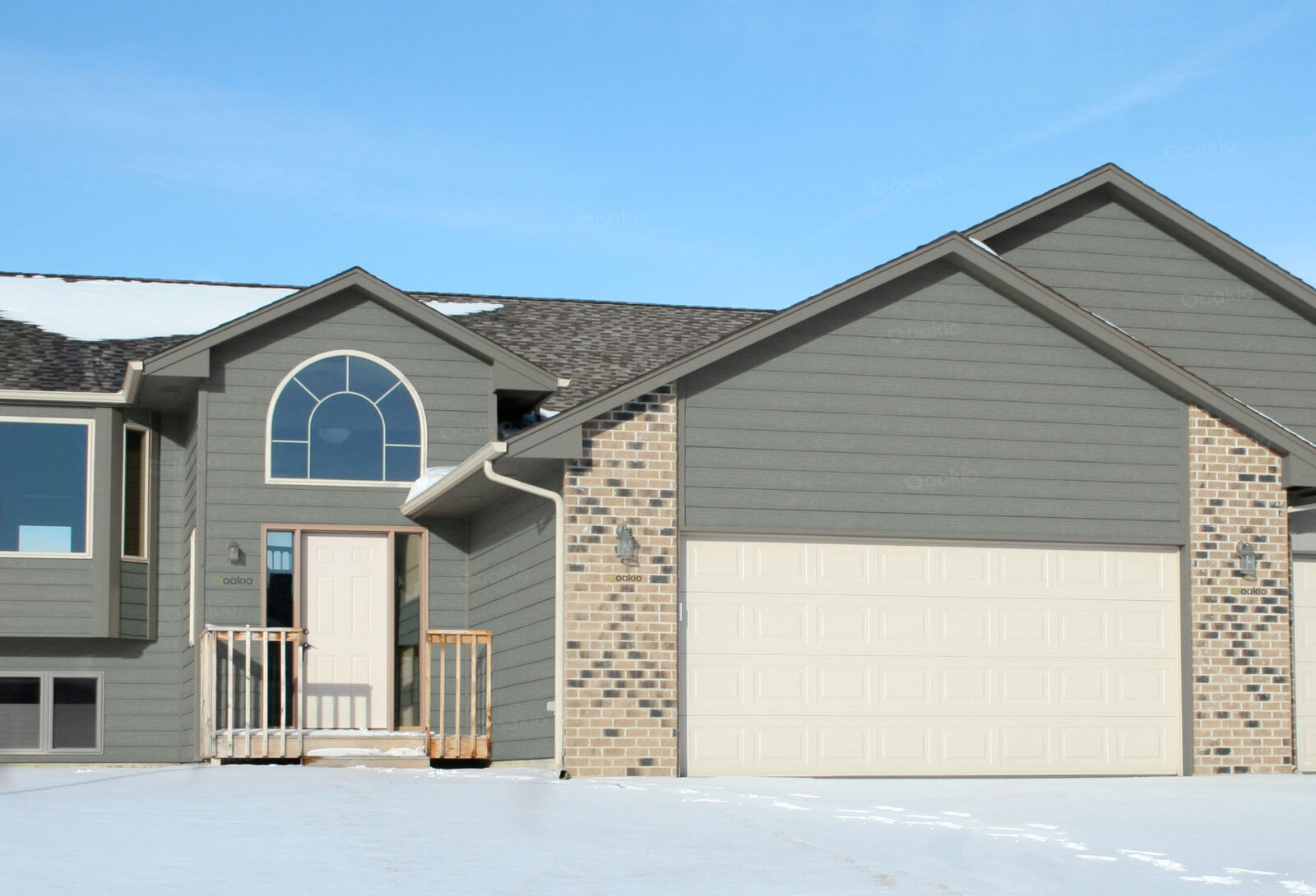 A driveway leading to a gray-colored house featuring a composite cladding system