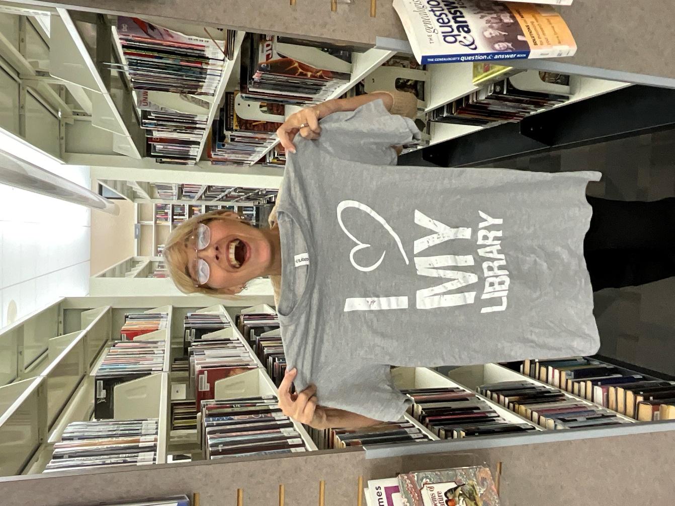 Happy librarian holds an I ❤ My Library t-shirt