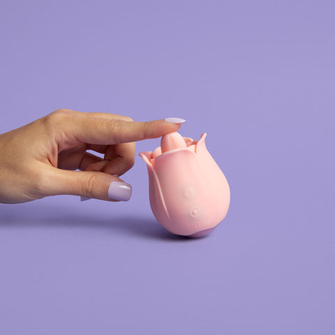 a finger touching the tongue of a pink flora rose toy