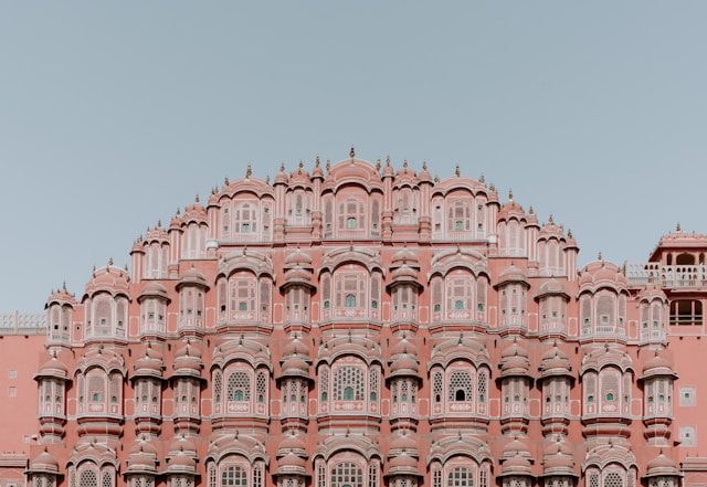 A majestic, intricately designed pink palace facade with numerous small windows showcases traditional building techniques.