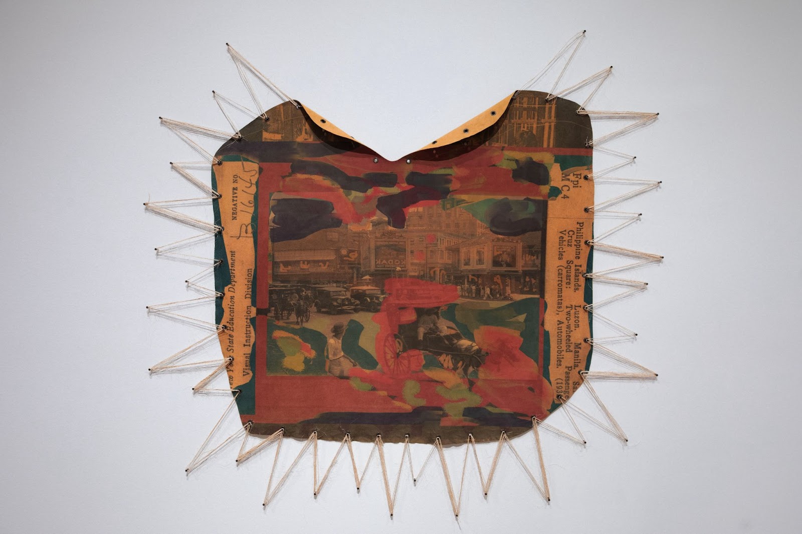 Image: Crystal Z Campbell, “Balat," 2024. Digital Collage on Suede, Grommets, Sisal. A concave circular work that's tan, black. green, and turquoise throughout with stringed spokes threaded between the piece and anchored to the wall. Photo Credit: St. Louis Art Museum. Courtesy of Crystal Z Campbell.