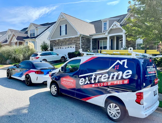 Branded Vehicles of Extreme Window Film in front of residential homes.