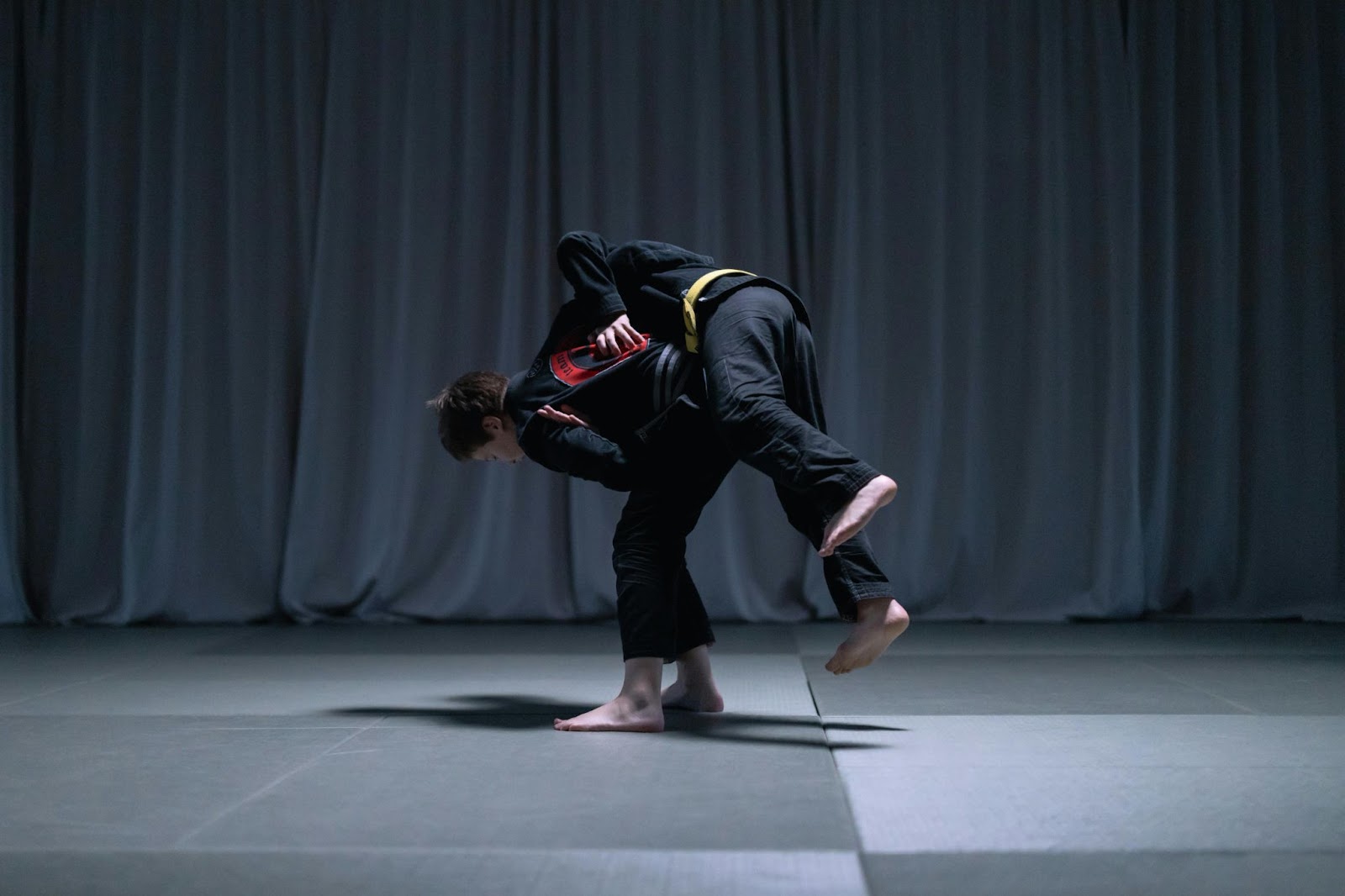 A young martial arts student performs a takedown on an opponent