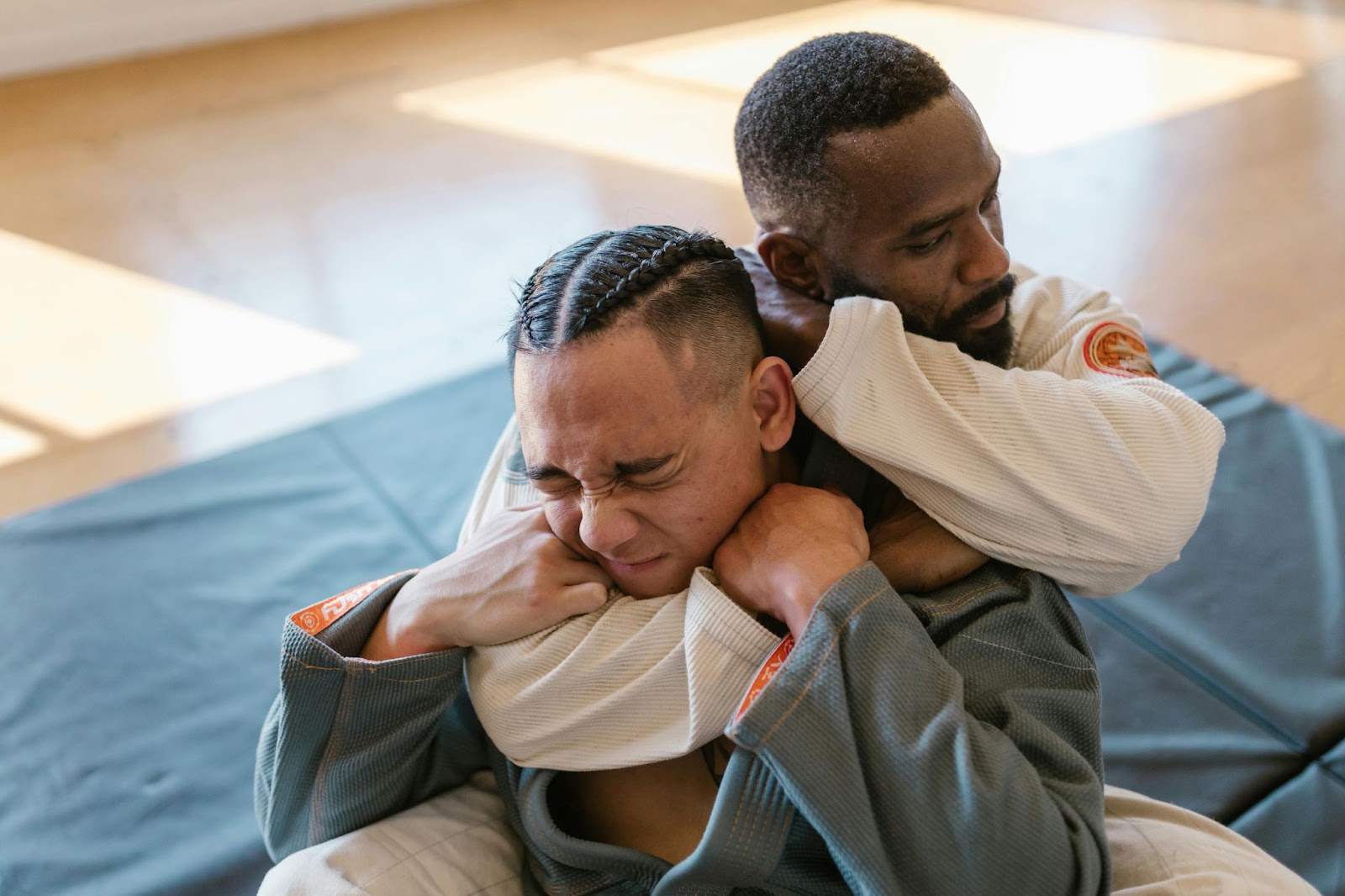 A martial arts instructor performing an elbow chokehold on a student 