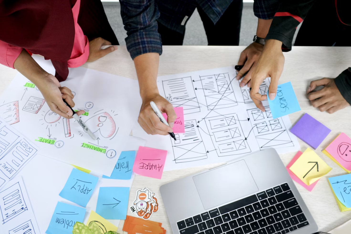 Multiple people brainstorming advertising campaign with colorful sticky notes and flow charts 
