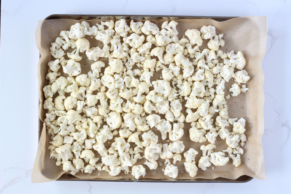 Raw cauliflower pieces on baking sheet