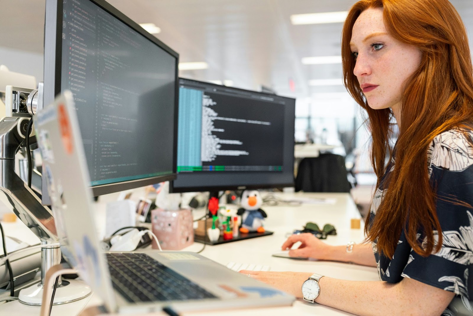 Woman working at the office on several monitors