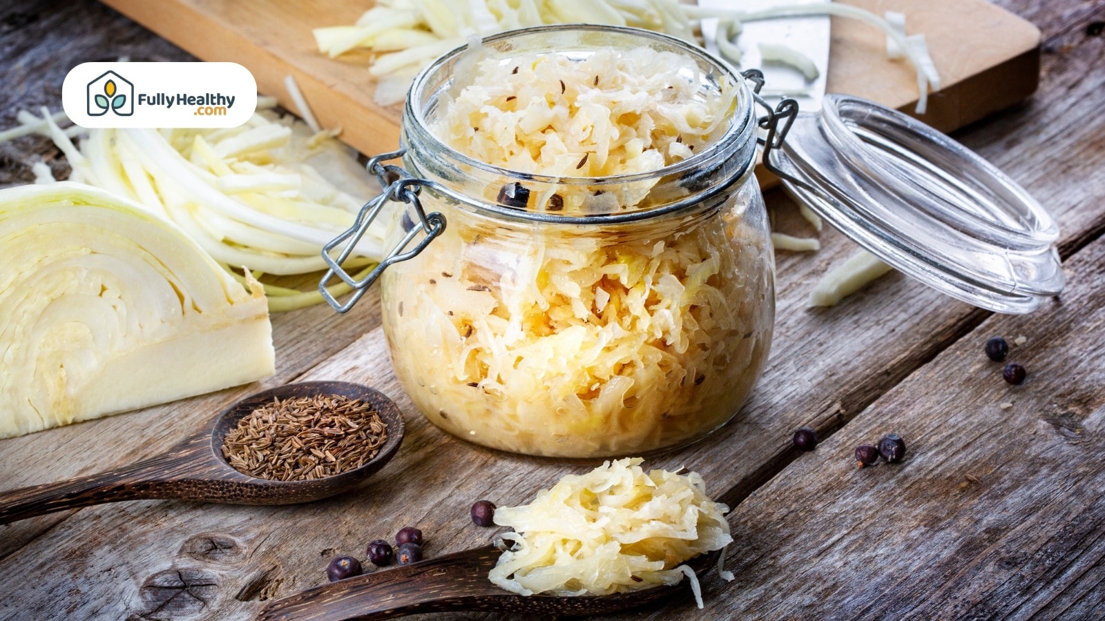 Glass jar of sauerkraut with cabbage and spices on table