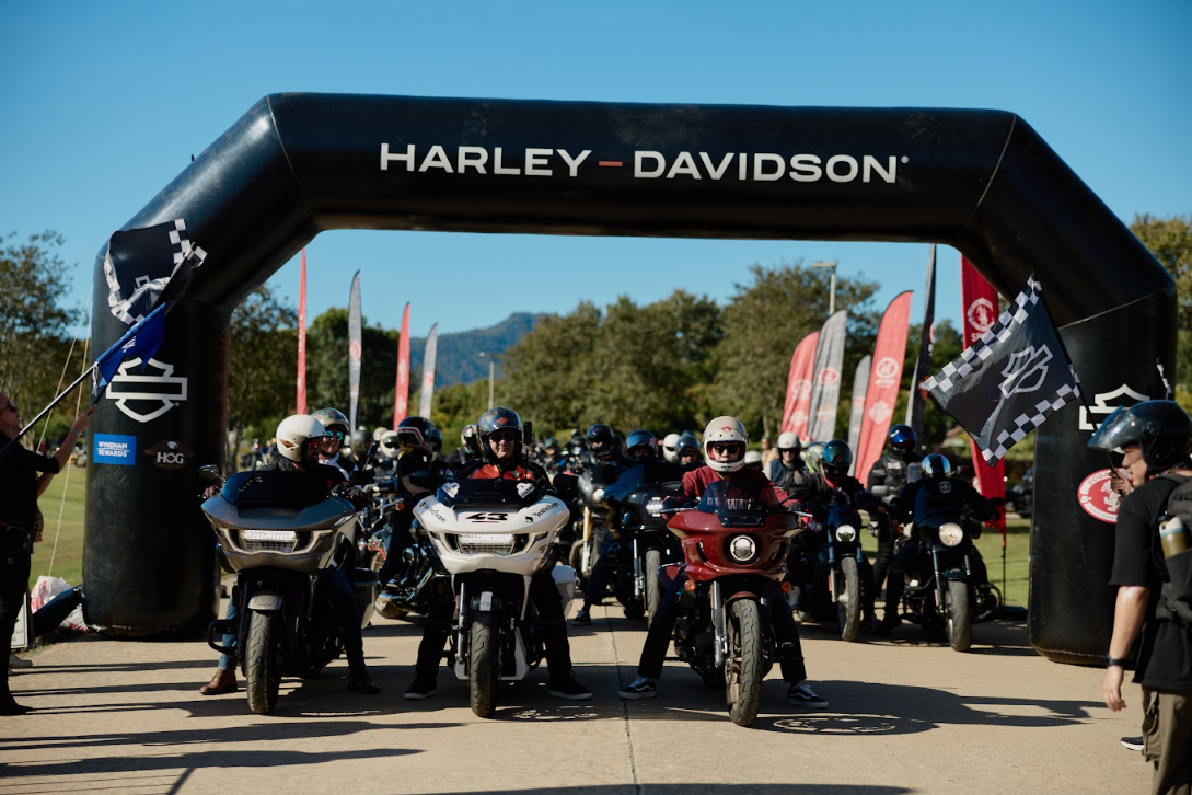 A group of people on motorcycles under a black arch

Description automatically generated