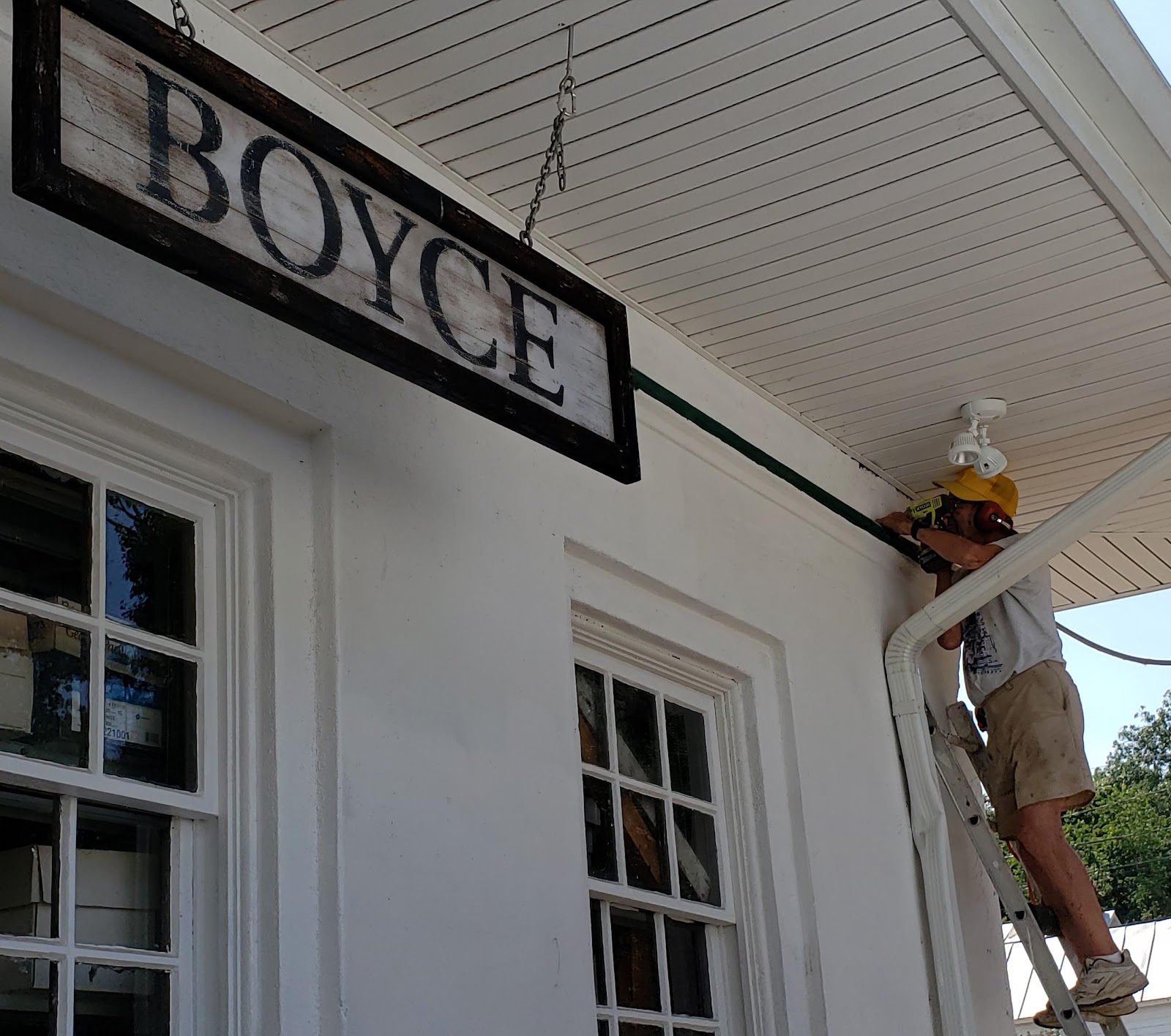 A person on a ladder on a white buildingDescription automatically generated